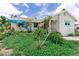 Exterior daytime view of home; the front yard is overgrown and minimal landscaping is present at 1580 Arizona Ave Ne, St Petersburg, FL 33703