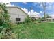 View of a grassy side yard and the exterior of the home; some flowers are in bloom at 1580 Arizona Ave Ne, St Petersburg, FL 33703