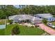 Inviting single-Gathering home featuring lush landscaping, a red brick driveway, and mature trees surrounding the property at 1607 New Bedford Dr, Sun City Center, FL 33573