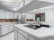 A bright kitchen with stainless steel refrigerator, white cabinets, island cooktop and a garden view at 1607 New Bedford Dr, Sun City Center, FL 33573
