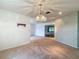 Spacious room featuring neutral carpeting, a decorative wall, and a vintage chandelier, blending comfort and style at 1607 New Bedford Dr, Sun City Center, FL 33573