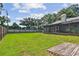 Large grassy backyard with screened patio area and wooden privacy fence at 17701 Sunrise Dr, Lutz, FL 33549