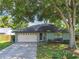 Charming single-story home featuring an attached garage and a lush, mature shade tree in the front yard at 17701 Sunrise Dr, Lutz, FL 33549