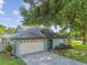 Single-story home featuring a two-car garage, light green exterior, and well-maintained landscaping at 17701 Sunrise Dr, Lutz, FL 33549