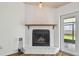 Living room white brick fireplace with a wooden mantle, and a view to the back yard at 17701 Sunrise Dr, Lutz, FL 33549