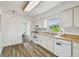A charming kitchen with wood-look flooring and white cabinetry, with a dining room view at 17701 Sunrise Dr, Lutz, FL 33549
