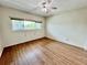 Spacious bedroom featuring wood-look laminate flooring, ceiling fan, and natural light from the window at 2341 Haitian Dr # 49, Clearwater, FL 33763