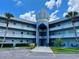 Low-angle view of the exterior of a light blue complex with palm trees, balconies and a central dome at 2341 Haitian Dr # 49, Clearwater, FL 33763