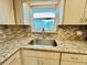 Close-up of the kitchen sink and countertop, showcasing the granite and mosaic tile backsplash at 2341 Haitian Dr # 49, Clearwater, FL 33763