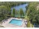 Aerial view of community pool area, surrounded by trees and a large lake at 2557 Laurelwood Dr # 10D, Clearwater, FL 33763