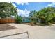 Aqua home with a long driveway and a fenced yard, surrounded by lush greenery at 301 Cevera Dr, Dunedin, FL 34698