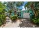 Bright blue home featuring a well-manicured lawn, palm trees, and a private garage entrance at 301 Cevera Dr, Dunedin, FL 34698