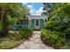 Charming home entrance surrounded by lush tropical landscaping and a welcoming covered porch at 301 Cevera Dr, Dunedin, FL 34698