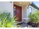 Welcoming entryway with a red front door, sidelight window, and lush landscaping at 3312 Francoa Dr, Odessa, FL 33556