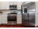 Close-up of kitchen appliances including stainless steel refrigerator, microwave, and gas range with white cabinetry at 3312 Francoa Dr, Odessa, FL 33556