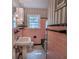 Charming bathroom featuring pink tile, black accents, and a classic pedestal sink at 3516 W Santiago St, Tampa, FL 33629