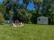 Large backyard with lush green grass, storage shed, and a cozy seating area with a fire pit at 37153 Mcminn Ave, Dade City, FL 33525