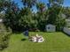 Aerial shot of a large backyard featuring an outdoor firepit seating area, storage shed, and privacy fence at 37153 Mcminn Ave, Dade City, FL 33525