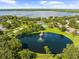 Wide aerial shot featuring a pond, tennis courts, and lush green landscaping, highlighting community amenities at 3772 Woodridge Pl, Palm Harbor, FL 34684