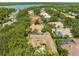 Aerial view of a lovely home nestled among lush greenery, showcasing a tile roof and sparkling screened-in pool at 3772 Woodridge Pl, Palm Harbor, FL 34684