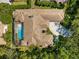 Aerial view of home featuring a tile roof, a screened-in pool and lush landscaping, showcasing its backyard oasis at 3772 Woodridge Pl, Palm Harbor, FL 34684