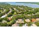 Aerial view of a residential neighborhood featuring homes with lush greenery and a beautiful lake in the background at 3772 Woodridge Pl, Palm Harbor, FL 34684