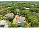Aerial view of home featuring a tile roof and a screened-in pool surrounded by lush greenery in a serene neighborhood at 3772 Woodridge Pl, Palm Harbor, FL 34684