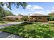 Charming brick home displays lush landscaping, a three-car garage, a curved driveway, and mature landscaping at 3772 Woodridge Pl, Palm Harbor, FL 34684