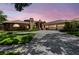 Elegant brick home with a well-manicured lawn and a three-car garage at sunset at 3772 Woodridge Pl, Palm Harbor, FL 34684