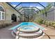 Beautiful screened-in pool with a hot tub and brick paved patio surrounded by lush landscaping at 3772 Woodridge Pl, Palm Harbor, FL 34684