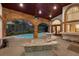 Inviting covered pool and patio area featuring exposed brick, ceiling fans and ample seating for outdoor relaxation at 3772 Woodridge Pl, Palm Harbor, FL 34684