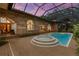 Beautiful in-ground pool with adjacent spa and screened enclosure attached to brick home with arched windows at 3772 Woodridge Pl, Palm Harbor, FL 34684