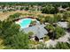 Aerial view of a large community pool with lounge chairs, umbrellas, and surrounding trees at 518 Winthrop Dr, Spring Hill, FL 34609