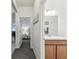 Hallway with gray carpet leads to the bathroom with light wood vanity and an entry to bedroom with nightstand at 518 Winthrop Dr, Spring Hill, FL 34609