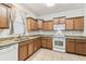 Well-lit kitchen featuring wood cabinets, tile floors, granite countertops, and white appliances at 518 Winthrop Dr, Spring Hill, FL 34609