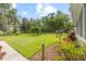 Expansive back yard with lush green lawn, mature trees, and landscaped garden areas at 523 2Nd Sw Ave, Lutz, FL 33548