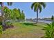 Spacious backyard featuring lush green grass, a pond, a white fence, and manicured tropical landscaping at 5710 Tortoise Pl, Apollo Beach, FL 33572