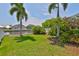 Beautiful waterfront backyard with lush landscaping, including palm trees and flowering bushes, near the water at 5710 Tortoise Pl, Apollo Beach, FL 33572