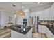 Bright kitchen with white cabinets, black countertops, stainless steel appliances, island, and wood flooring at 5710 Tortoise Pl, Apollo Beach, FL 33572