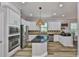 Bright kitchen features stainless steel appliances, black countertops, kitchen island, and light wood flooring at 5710 Tortoise Pl, Apollo Beach, FL 33572