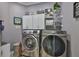 Laundry room featuring gray walls, white cabinets, a sink, and a front loading washer and dryer at 5710 Tortoise Pl, Apollo Beach, FL 33572