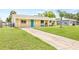 Exterior view of a single-story home with a well-maintained lawn and a long driveway at 6012 Flora Ter, Apollo Beach, FL 33572