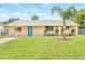 Charming single-story home with a well-manicured lawn and a vibrant blue front door, enhanced by a decorative palm tree at 6012 Flora Ter, Apollo Beach, FL 33572