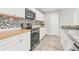 Updated kitchen features sleek black appliances, white cabinets, butcher block countertops, and stylish mosaic backsplash at 6012 Flora Ter, Apollo Beach, FL 33572