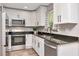 Modern kitchen featuring white cabinets, granite countertops, stainless steel appliances and a window view at 604 Kinnear Dr, Brooksville, FL 34601