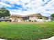 Sprawling home exterior featuring a well-maintained lawn and mature trees against a blue sky at 8110 Damara Dr, New Port Richey, FL 34653