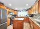 Well-equipped kitchen with wood cabinets, granite countertops, and stainless steel appliances at 8110 Damara Dr, New Port Richey, FL 34653