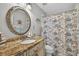 Bright bathroom featuring granite counters, a decorative mirror, and a floral shower curtain, blending style and functionality at 9220 Hidden Water Cir, Riverview, FL 33578