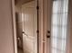 White bathroom door opening into a room with wallpapered walls and tiled floors at 1039 Greenturf Rd, Spring Hill, FL 34608