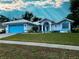 Charming one-story home with white exterior, blue trim, well-manicured lawn, and blue garage door at 1039 Greenturf Rd, Spring Hill, FL 34608